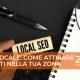 Una scrivania su cui poggia un quaderno, degli occhiali da vista ed una mano con un piccolo foglio, con la scritta "local seo"