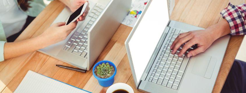 come-strutturare-una-campagna-pubblicitaria-di-successo Due persone sedute a un tavolo lavorano su laptop e collaborano su un progetto