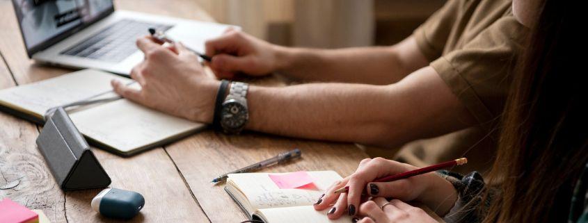Due persone al tavolo con un laptop e un quaderno