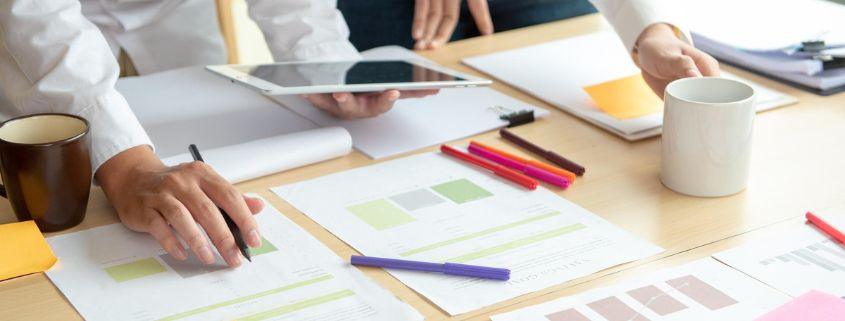 cos-e-il-rebranding-digitale-e-quando-e-necessario Un gruppo di persone collabora a un progetto attorno a un tavolo, con computer e documenti sparsi